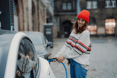 Femme heureusement en train de recharger son véhicule électrique