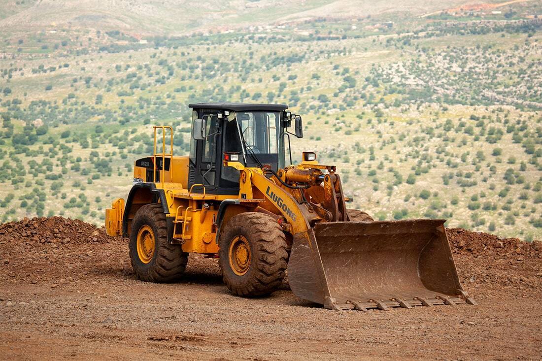 Tractopelle jaune sur un chantier dans un paysage valloné